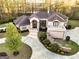Aerial view of a luxurious, light pink stucco home with a winding driveway and professionally landscaped front yard near a lake at 2279 Fieldstone Dr, Conyers, GA 30013