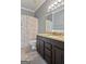 Stylish bathroom with modern vanity, granite countertop, decorative mirror, and a shower featuring a patterned curtain at 131 Pecan Lake Dr, Sharpsburg, GA 30277