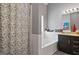 Bathroom featuring a tub with decorative shower curtain, tile surround, vanity with granite countertop and cabinets at 131 Pecan Lake Dr, Sharpsburg, GA 30277