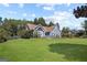 Beautiful exterior showcasing a blue stucco house on a vast green lawn, surrounded by trees at 131 Pecan Lake Dr, Sharpsburg, GA 30277