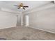 A large bedroom with neutral walls, beige carpet, and a ceiling fan at 1064 Lear Dr, Locust Grove, GA 30248