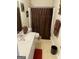 Well-lit bathroom featuring a wide mirror, a dark brown shower curtain, and neutral tile flooring at 2626 Summit Sw Pkwy, Atlanta, GA 30331