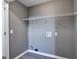 A grey laundry room with washer/dryer hookups, grey vinyl floor, and white wire rack shelving at 1515 Summer Lake Ter, Loganville, GA 30052