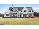 Charming two-story home featuring a black front door, white siding, rocking chairs, and a well-maintained lawn at 105 Coogler Way, Brooks, GA 30205