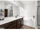 Bathroom featuring dual sinks, tub, white walls, and a large mirror at 243 Summergate Ln, Villa Rica, GA 30180