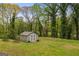 View of backyard featuring a well maintained shed with a painted exterior and surrounded by a lush lawn and mature trees at 2341 Elmwood Se Cir, Atlanta, GA 30339