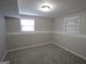 An empty bedroom with gray carpet, two windows, and gray walls, ready for personalization at 1897 Madras Ct, Lithonia, GA 30058