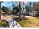 Beautiful backyard with stone patio, manicured lawn, mature trees, a pool, and covered outdoor seating area at 610 Graystone Ct, Peachtree City, GA 30269