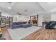 Open-concept living room with stone fireplace, hardwood floors, built-in bookshelves, modern sofa, and an adjacent kitchen at 610 Graystone Ct, Peachtree City, GA 30269