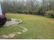 The expansive backyard features a fire pit, a lush lawn, and is bordered by mature trees at 711 Lily Glen Ln, Stockbridge, GA 30281
