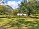 Sprawling backyard with lush lawn, mature trees, and charming home in the background at 1202 Coan Dr, Locust Grove, GA 30248