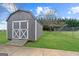 Backyard shed with barn doors, painted gray with white trim and a ramp at 280 Nutt Dr, Locust Grove, GA 30248