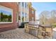 Outdoor kitchen with a built-in grill, set on a stone patio near a brick home with large windows at 3149 Hidden Falls Ne Dr, Buford, GA 30519