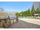 Outdoor kitchen area with grill, adjacent to a pool and lush backyard landscaping for great entertaining at 3149 Hidden Falls Ne Dr, Buford, GA 30519