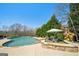 Backyard view of a kidney-shaped pool surrounded by trees, patio furniture, and landscaping at 3149 Hidden Falls Ne Dr, Buford, GA 30519