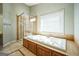 Bright bathroom featuring a standalone shower with beige tile and a soaking tub under a window at 132 Westmont Way, Tyrone, GA 30290