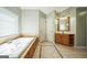 A bathroom is tiled with a bathtub with wood trim, and a sink vanity at 132 Westmont Way, Tyrone, GA 30290