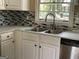 Bright kitchen with a stainless steel sink, modern fixtures, and sleek backsplash under a window at 1271 Sanders Dr, Lake City, GA 30260