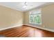 Sunlit bedroom with hardwood floors, neutral paint, a ceiling fan, and a large window with views of the backyard at 1301 Blue Sky Ct, Peachtree City, GA 30269