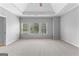 Spacious bedroom with tray ceiling features carpet floors and three windows at 1301 Blue Sky Ct, Peachtree City, GA 30269