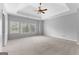 Spacious bedroom with tray ceiling features carpet floors and three windows at 1301 Blue Sky Ct, Peachtree City, GA 30269