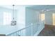 Second floor hallway with modern chandelier and white railing at 8030 Snapwell Dr, Fairburn, GA 30213