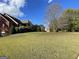 Expansive backyard with a lush lawn, mature trees, and neighboring homes in the distance at 239 Overland Trl, Mcdonough, GA 30252