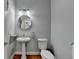 Powder room with pedestal sink, round mirror, and decorative light fixture at 4852 Jacobs Cove Pt, Buford, GA 30519