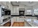 Modern kitchen with stainless steel appliances, black backsplash, and white custom cabinetry at 4852 Jacobs Cove Pt, Buford, GA 30519
