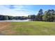 Scenic lake view with lush green lawn and mature trees, offering a serene and picturesque setting for lakeside living at 4852 Jacobs Cove Pt, Buford, GA 30519