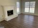 Spacious living room featuring a cozy fireplace, hardwood floors, and two large windows at 1126 Old Jackson Rd, Locust Grove, GA 30248