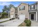 Beautiful exterior view of tan townhouses with brick accents, driveways, and green landscaping at 1310 Rogers Trce, Lithonia, GA 30058