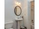 Bright bathroom features a pedestal sink, oval mirror, and shower with white tile surround at 265 Ridgewood Dr, Fayetteville, GA 30215