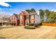 Beautiful two-story red brick home featuring meticulously landscaped grounds and lush trees at 265 Ridgewood Dr, Fayetteville, GA 30215