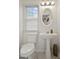 Clean half-bath featuring pedestal sink, oval mirror, and modern toilet; natural light from window at 109 Bowen Cir, Atlanta, GA 30313