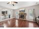 Living room with a stone fireplace, hardwood floors, a ceiling fan, and a view to the kitchen at 605 Camano Way, Mcdonough, GA 30253