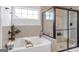 Bright bathroom featuring a soaking tub, glass-enclosed shower, and tiled walls at 8110 Brewton Bnd, Cumming, GA 30028