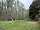Secluded small red shed on a grassy lot surrounded by tall trees and natural foliage at 4389 & 4381 Campbell Rd, Snellville, GA 30039