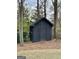 A stained, wooden shed with a gabled roof nestled among mature trees in the backyard at 497 Pine Haven Ln, Atlanta, GA 30342
