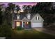 Charming two-story home with brick accents, dormer windows, and an attached two-car garage at dusk at 115 Brook Hollow Dr, Mcdonough, GA 30252