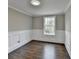 A bright, empty bedroom with dark hardwood floors, white trim and wainscoting, and a window with a view at 5155 Rosestone Nw Dr, Lilburn, GA 30047
