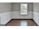 A vacant, light-filled room showcasing pristine white trim, wainscoting, and hardwood floors that complement the neutral walls at 5155 Rosestone Nw Dr, Lilburn, GA 30047