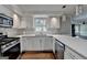 Bright, white eat in kitchen features stainless steel appliances and modern pendant lighting at 5155 Rosestone Nw Dr, Lilburn, GA 30047