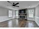 Well-lit living room featuring a cozy stone fireplace, hardwood floors, and a modern ceiling fan at 5155 Rosestone Nw Dr, Lilburn, GA 30047