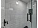 Close up of a luxurious glass enclosed shower featuring black hardware and marble tile walls at 5155 Rosestone Nw Dr, Lilburn, GA 30047