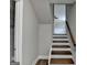 Stairway leading to a bright, neutral-toned space with hardwood steps, wooden handrail, and view of an adjacent bathroom at 5155 Rosestone Nw Dr, Lilburn, GA 30047