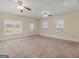 Spacious living room with plush carpeting, ceiling fans, and natural light from multiple windows at 105 Overlook Dr, Mcdonough, GA 30252