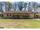 Charming brick ranch home with a manicured lawn, blossoming azaleas, and an attached garage at 447 Wavelyn Way, Riverdale, GA 30274