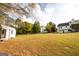 A spacious backyard featuring a grassy lawn, mature trees, and a view of the main house and outbuilding at 237 Summerford Pl, Stockbridge, GA 30281