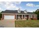 Charming brick home featuring a well-manicured lawn, dormer windows, and a cozy front porch with rocking chairs at 237 Summerford Pl, Stockbridge, GA 30281